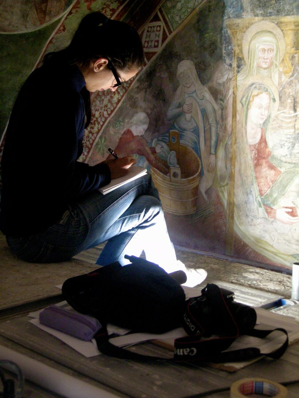 Eleonora Cigognetti mentre documenta e prende appunti davanti a un affresco storico